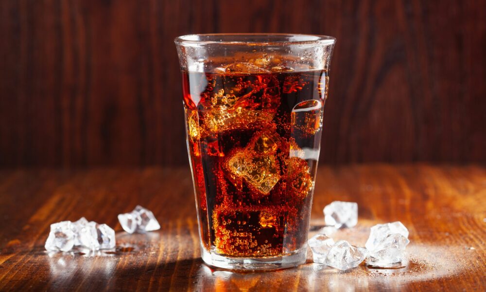 glass of cold cola soft drink with ice on wooden background