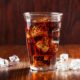 glass of cold cola soft drink with ice on wooden background